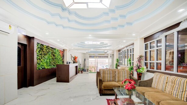 A lobby with a reception desk, sofas, a coffee table, and a decorative wall. - Hotel Mahadev Palace (Deoghar)