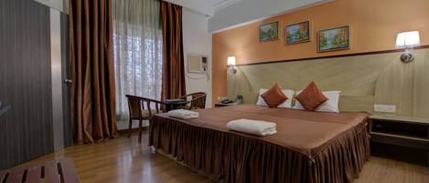 Habitación de hotel con una cama grande, un escritorio, una silla y un ventilador de techo.