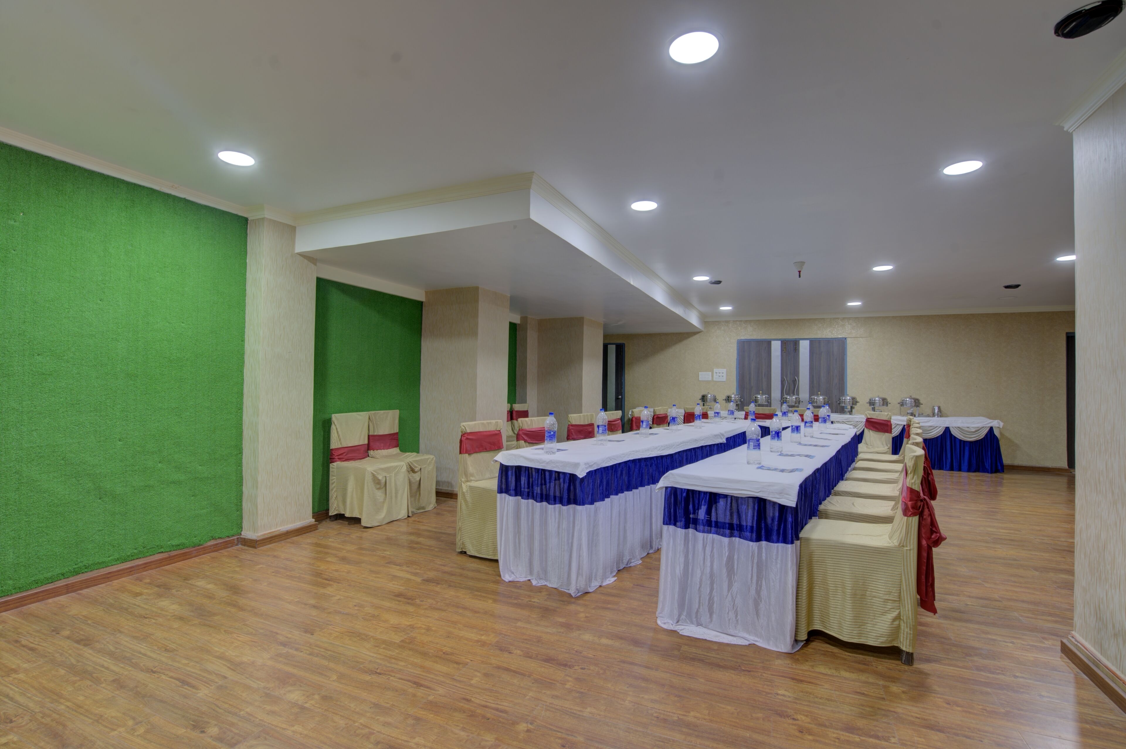 Une salle de conférence avec de longues tables, des chaises et un mur vert.
