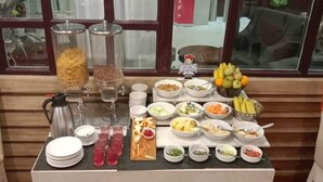 A buffet table with various dishes and drinks, including fruits, vegetables, and a coffee station. - Hotel Mahadev Palace (Deoghar)