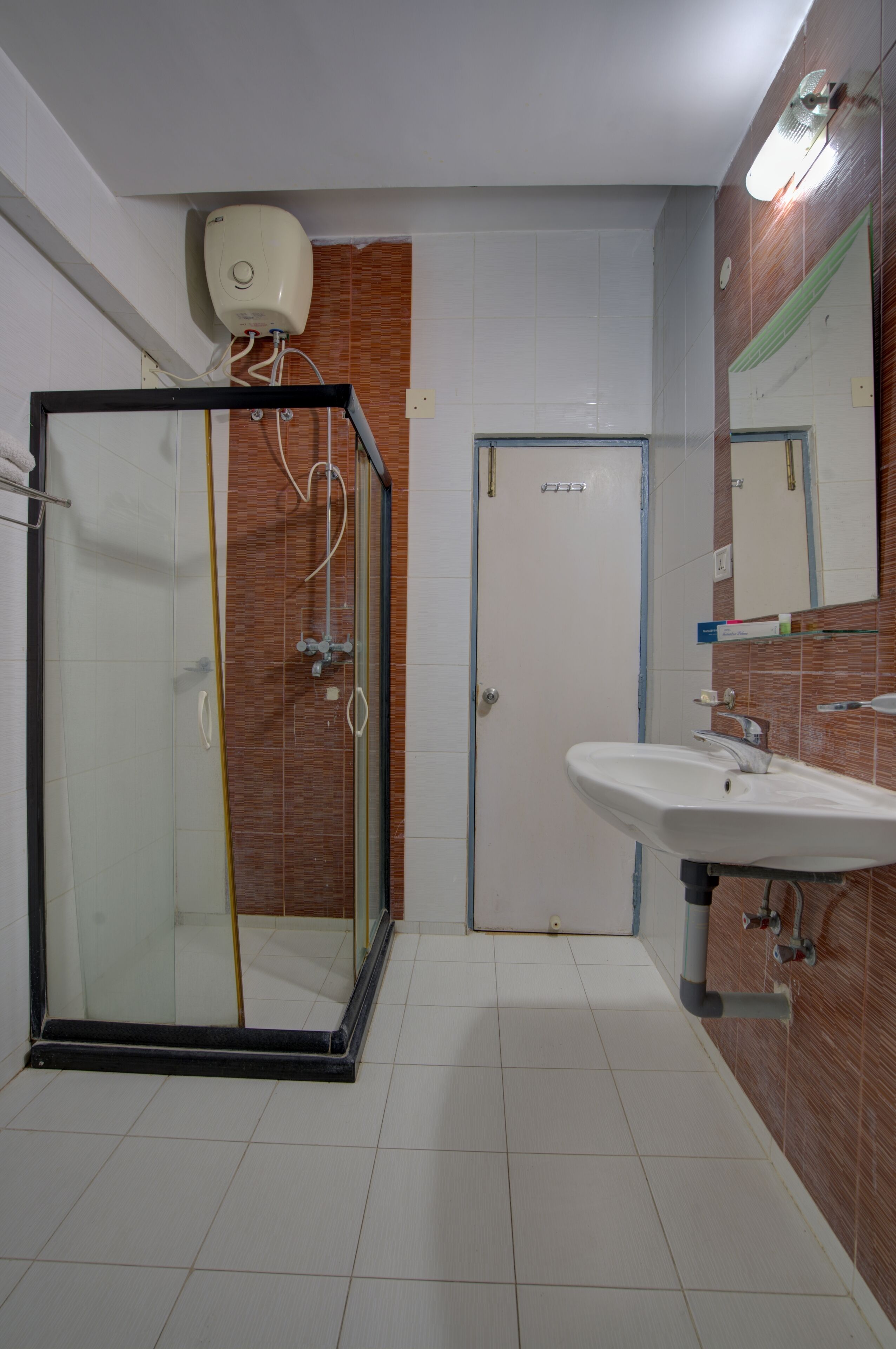 Une salle de bain avec une douche à parois de verre, un lavabo blanc et un sol carrelé.