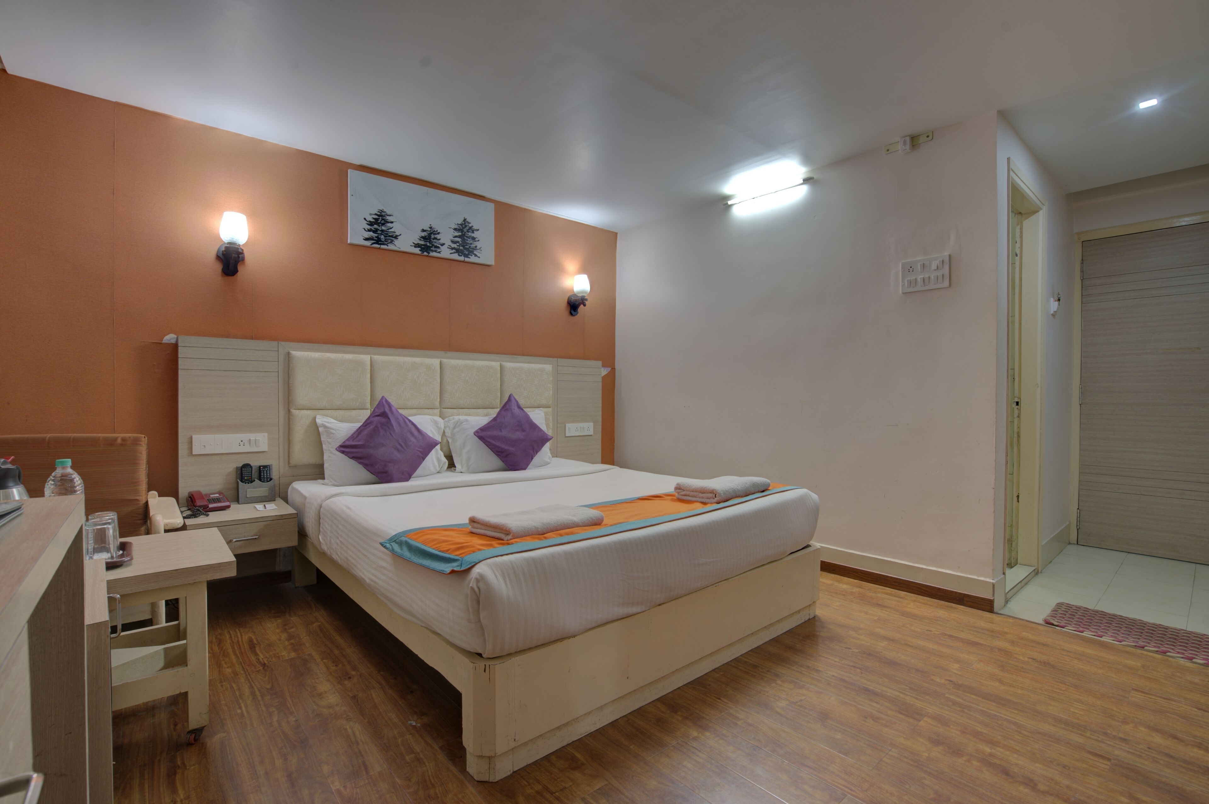 Un dormitorio ordenado con cama, mesitas de noche y un escritorio.