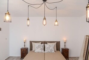 A bedroom with a bed, two bedside tables, and three hanging light fixtures.