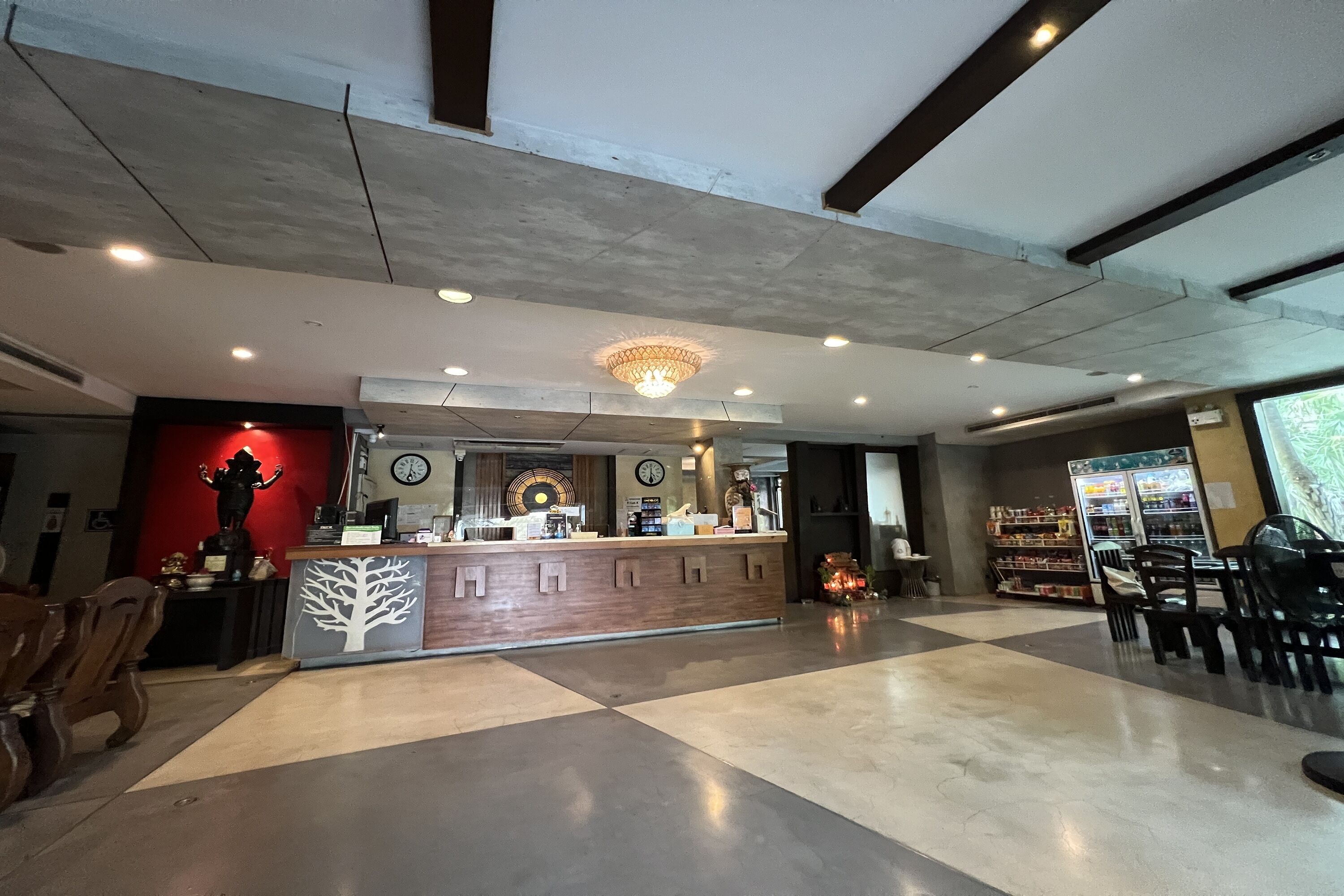 Eine geräumige Lobby mit einer Rezeption, einer Uhr und einer dekorativen Baumskulptur.