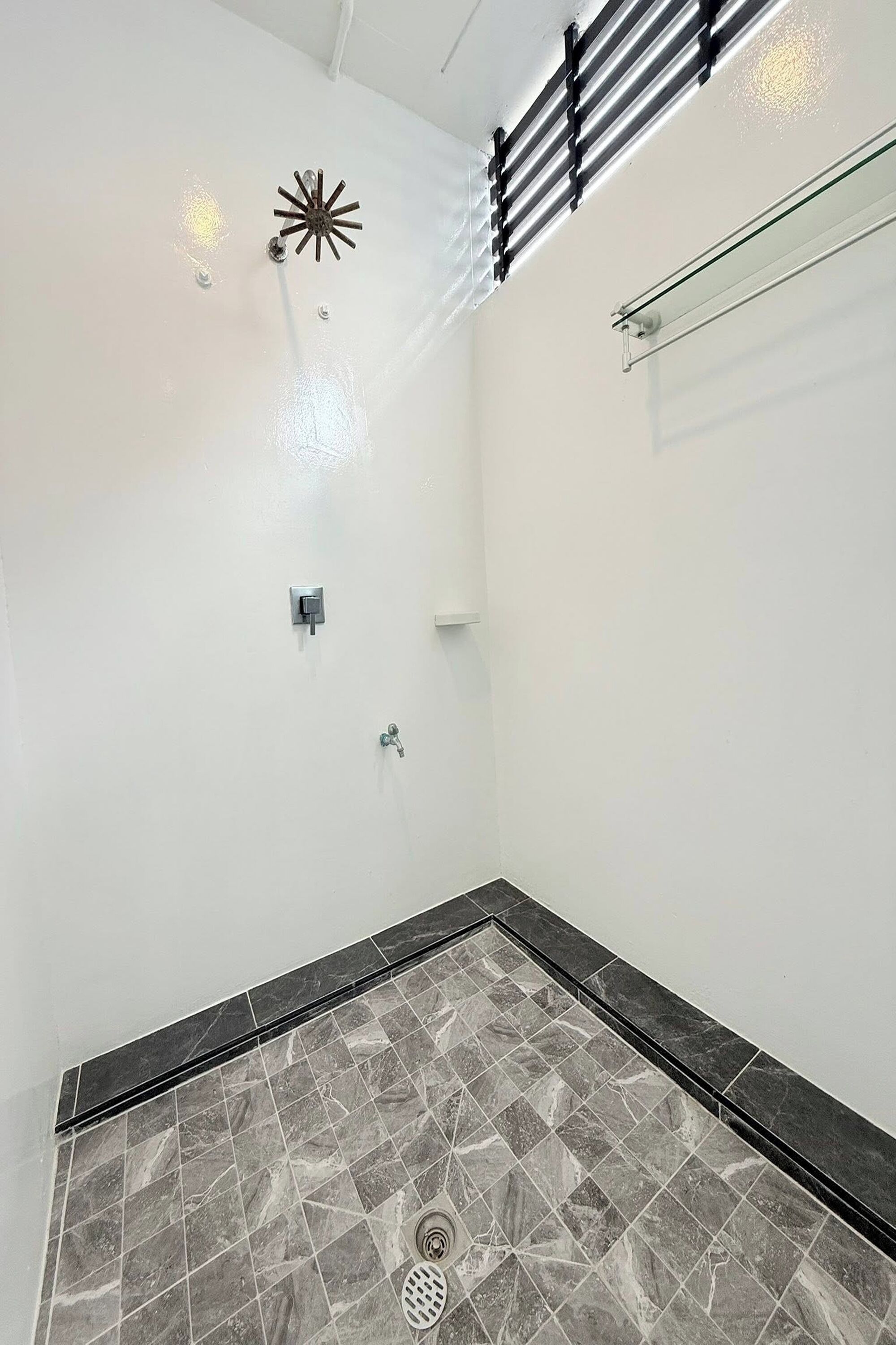 A bathroom with a shower, a towel rack, and a tiled floor.