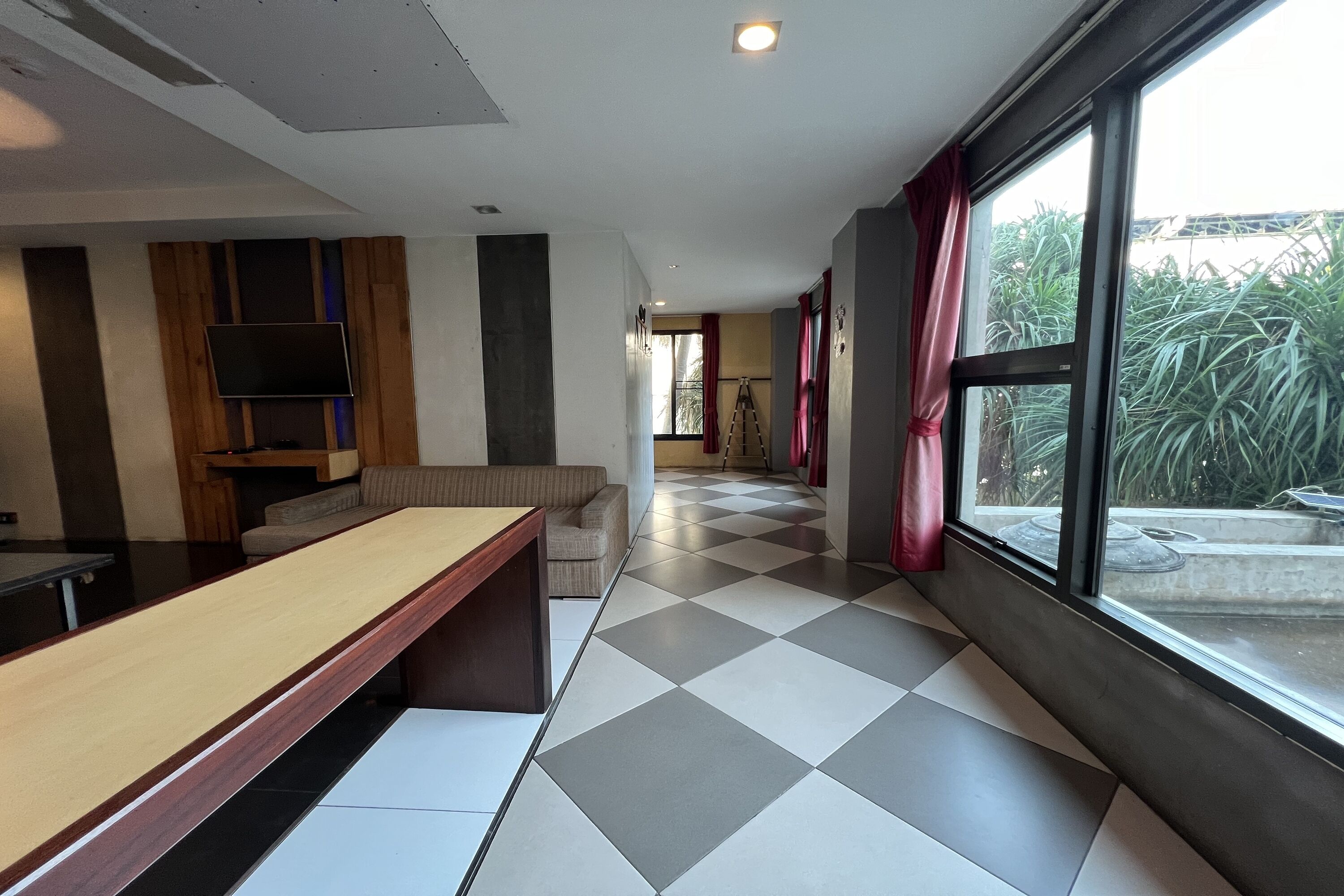 A modern room with a long wooden table, a sofa, and a TV mounted on the wall.