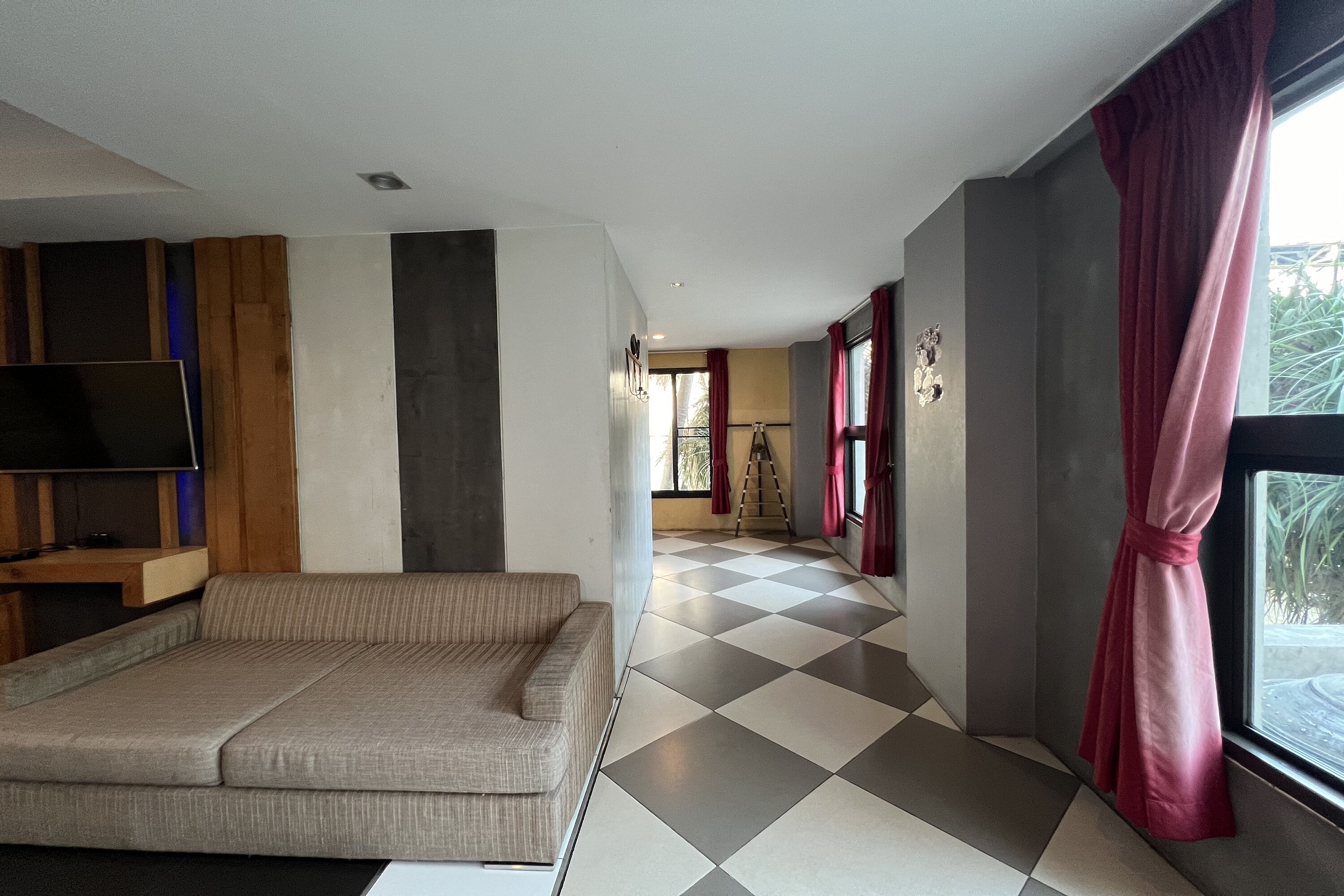 A modern living room with a sofa, a flat-screen TV, and a checkered floor.
