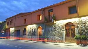 Un edificio con fachada de piedra, ventanas arqueadas y un balcón.