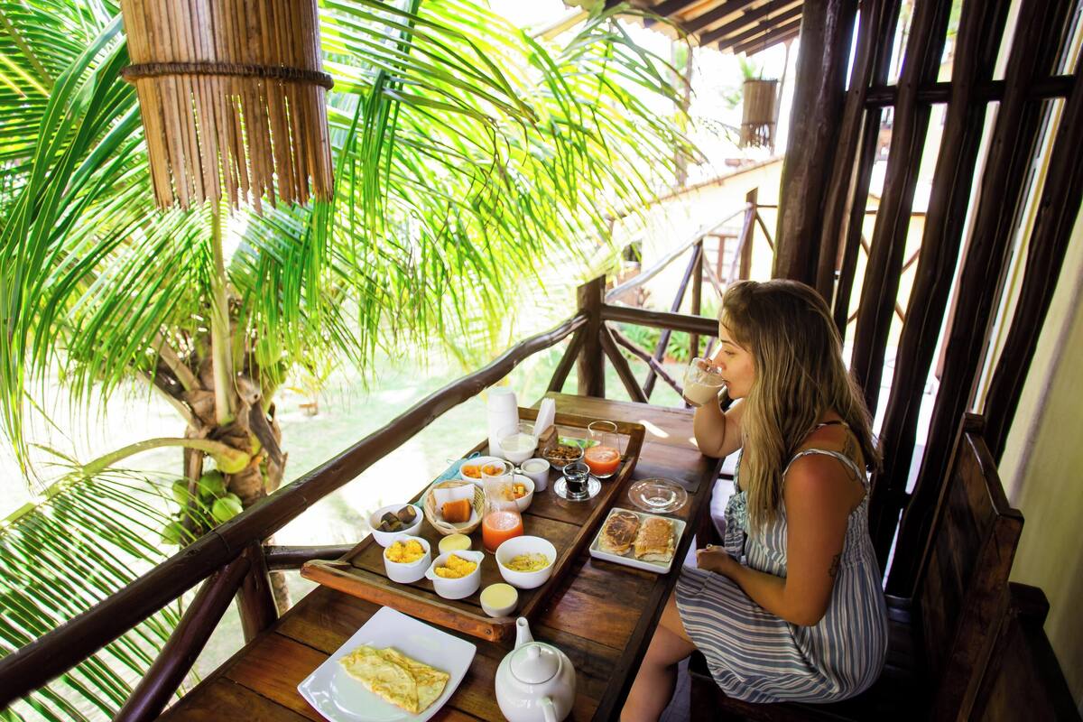 A wooden deck with a table set for breakfast, surrounded by lush greenery.