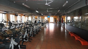 A gym with rows of stationary bikes, weight machines, and a mirrored wall.