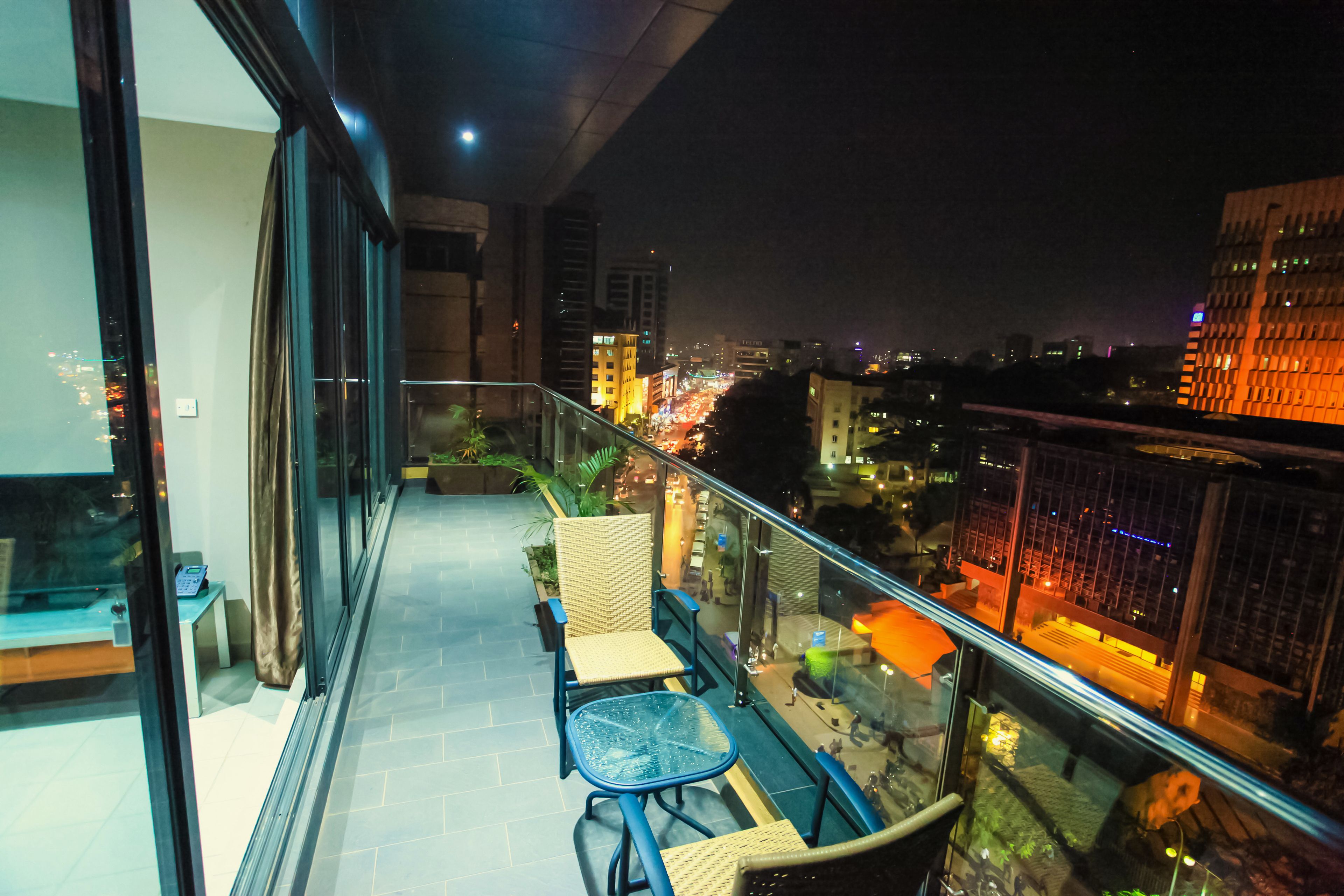 A balcony with a glass railing, wicker chairs, and a small table.