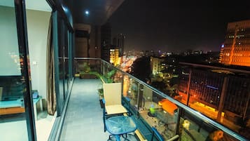A balcony with a glass railing, wicker chairs, and a small table.