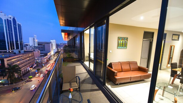 Een moderne hotelkamer met een balkon met uitzicht op een levendige straat en stadsbeeld.