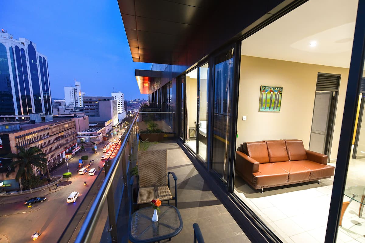 Habitación de hotel moderna con balcón que da a una calle concurrida y al paisaje urbano.