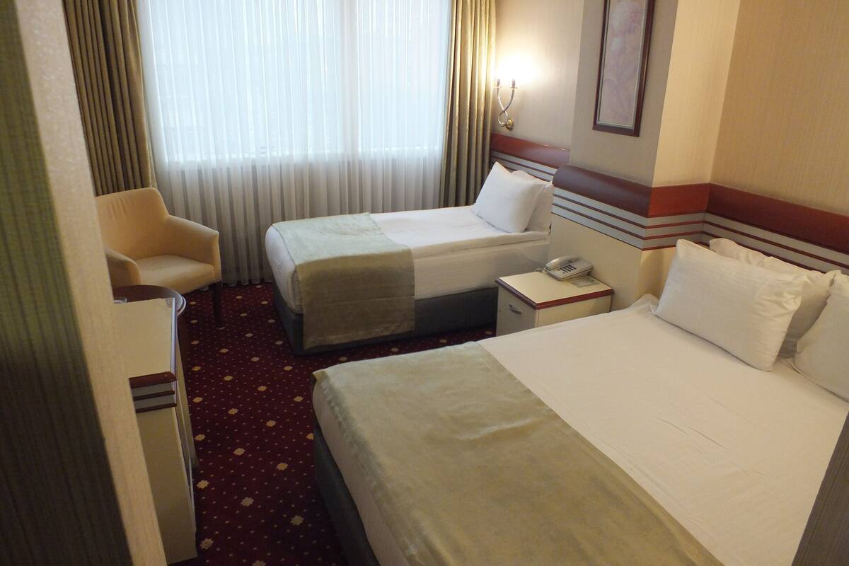 Habitación de hotel con dos camas, una mesita de noche con teléfono y una silla.