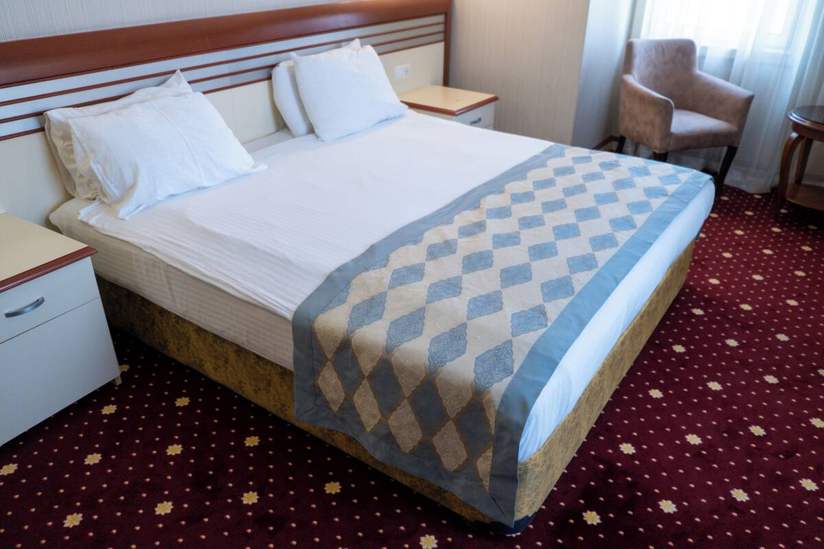 Una habitación de hotel con una cama, una mesita de noche, una silla y una pequeña mesa.