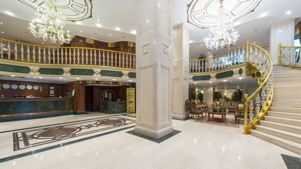 A grand lobby with a marble floor, a reception desk, and a grand staircase with a golden railing. - Akar International Hotel (Ankara)