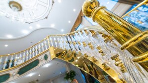 A grand, ornate staircase with golden railings and crystal decorations, leading to an upper floor. - Akar International Hotel (Ankara)