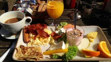 A breakfast tray with scrambled eggs, bacon, toast, a glass of orange juice, a salad, and a yogurt parfait.