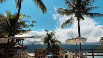 Relax by the serene pool surrounded by lush palm trees and a wooden deck.