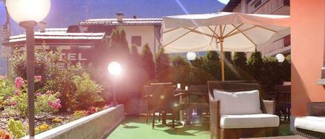 An outdoor patio with a seating area, a lamp post, and a view of a mountain.