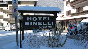 A snow-covered sign for Hotel Binelli with a parking sign indicating reserved parking for clients. - Hotel Binelli (Pinzolo)
