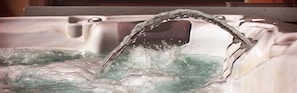 A hot tub with water flowing from a spout.