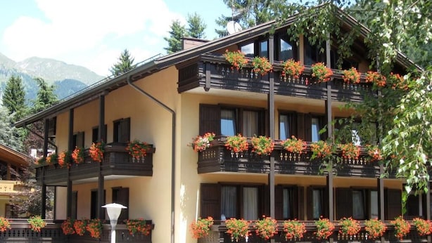 A multi-story building with balconies adorned with flower boxes. - Hotel Binelli (Pinzolo)
