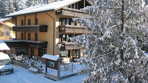 A multi-story building with balconies, surrounded by snow-covered trees. - Hotel Binelli (Pinzolo)