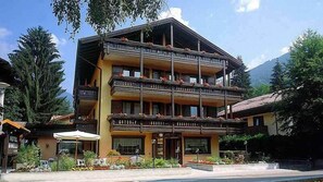 A multi-story hotel with balconies, a restaurant, and a mountain backdrop.