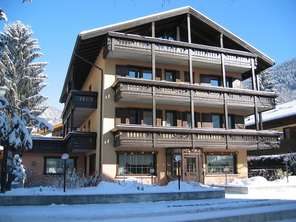 A multi-story hotel with balconies and a ski resort backdrop.