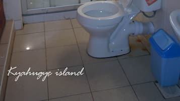 A bathroom with a glass-enclosed shower, a toilet, and a blue trash bin.