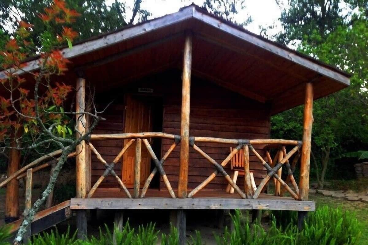 Uma cabana de madeira com varanda e porta.