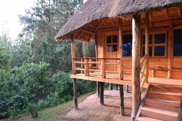 Una cabaña de madera con techo de paja, un balcón y una escalera que lleva a la entrada.