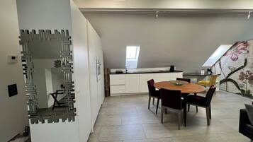 Eine moderne Küche mit einer zentralen Kochinsel, weißen Schränken und einem Essbereich mit rundem Tisch und Stühlen.