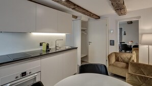 A modern kitchen with white cabinets, a black countertop, and exposed wooden beams on the ceiling. - The Residence La Cittadella (Baden)