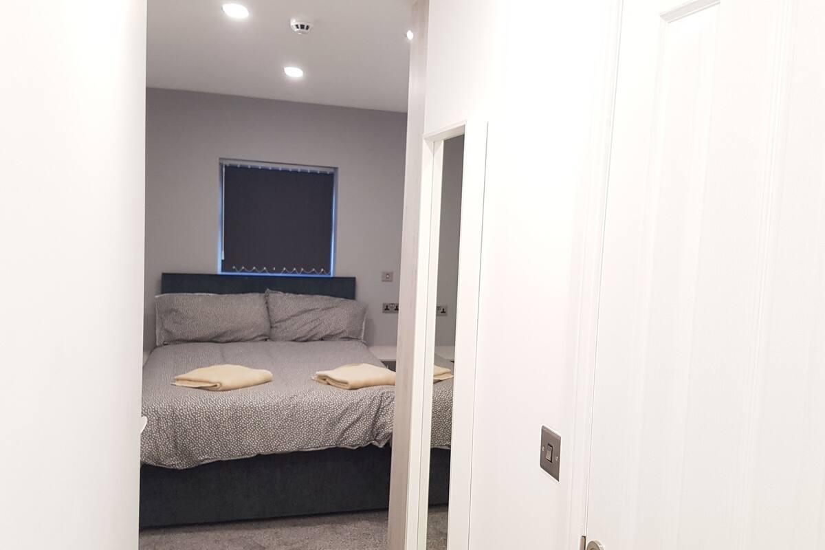 A bedroom with a bed, pillows, and a window.