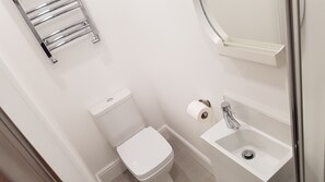 A small, white bathroom with a toilet, a sink, and a towel rack. - Central City House (Liverpool)