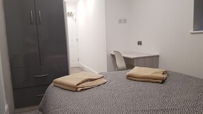 A small, neatly organized bedroom with a bed, a desk, and a wardrobe. - Central City House (Liverpool)