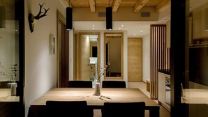 A dining area with a wooden table, chairs, a vase with flowers, and a mounted deer head on the wall. - EVA Apartments (Zermatt)