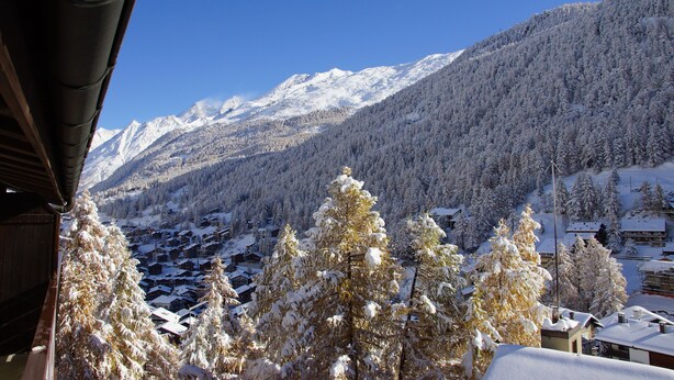 A snow-covered mountain landscape with a village in the valley. - EVA Apartments (Zermatt)