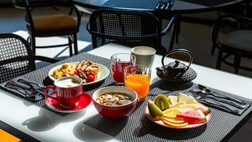 Ett frukostbord med en skål med flingor, en kopp kaffe, ett glas apelsinjuice och en tallrik med frukt.