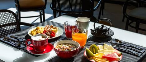Een ontbijttafel met een kom ontbijtgranen, een kop koffie, een glas sinaasappelsap en een schaal fruit.