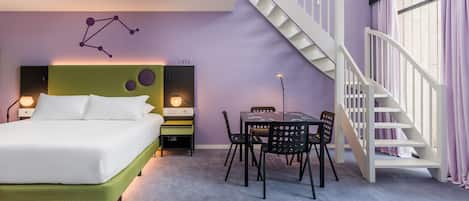 A bedroom with a bed, a desk, chairs, a staircase, and a wall with a constellation design.