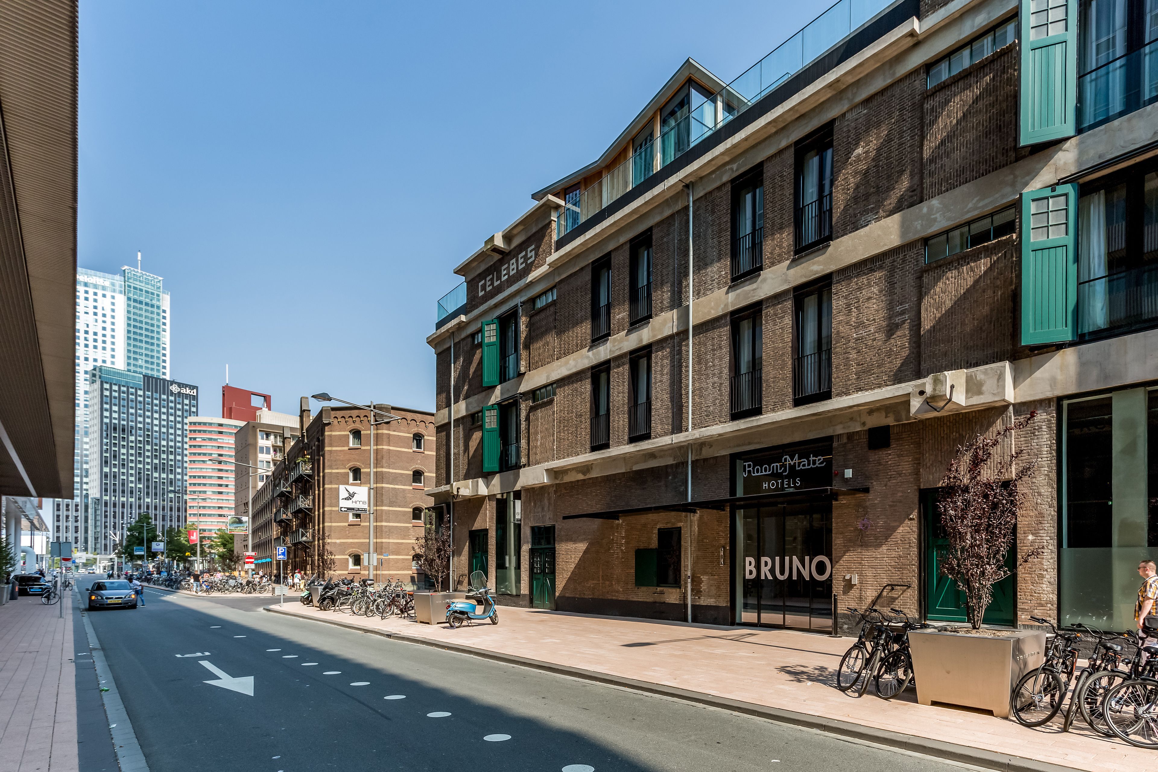 Un edificio a più piani dal design moderno, con un ristorante chiamato "BRUNO" e un hotel, RoomMate Hotels.