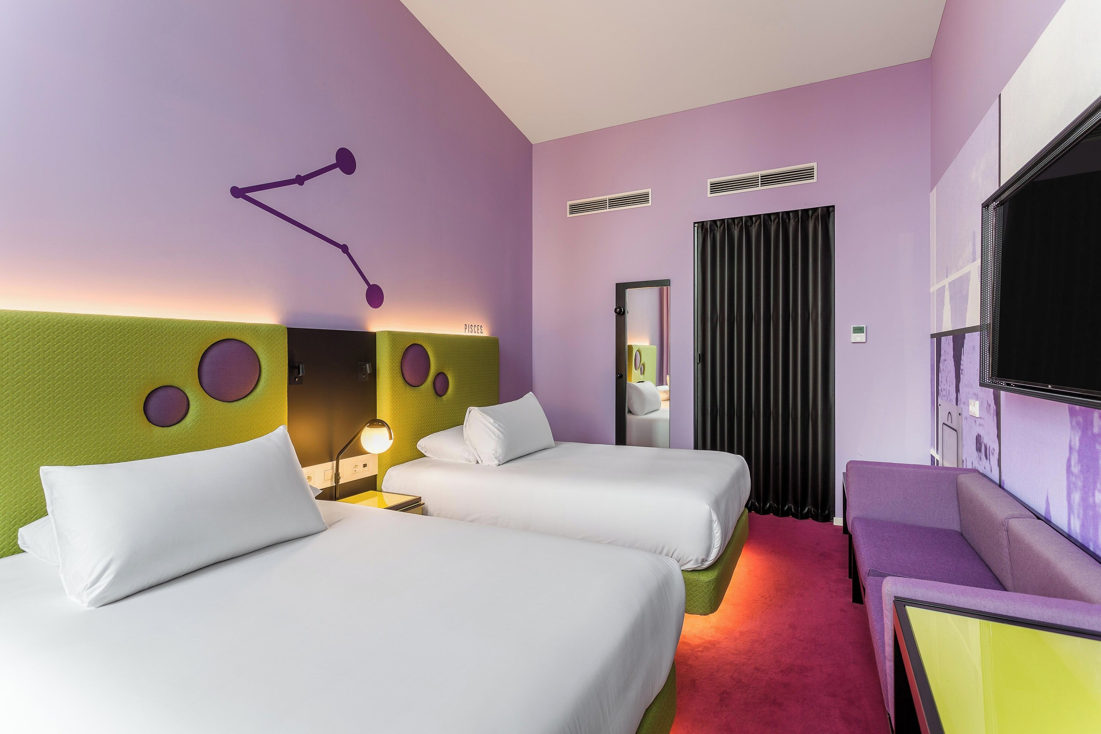 Une chambre d’hôtel avec deux lits, un canapé, une télévision et un miroir.