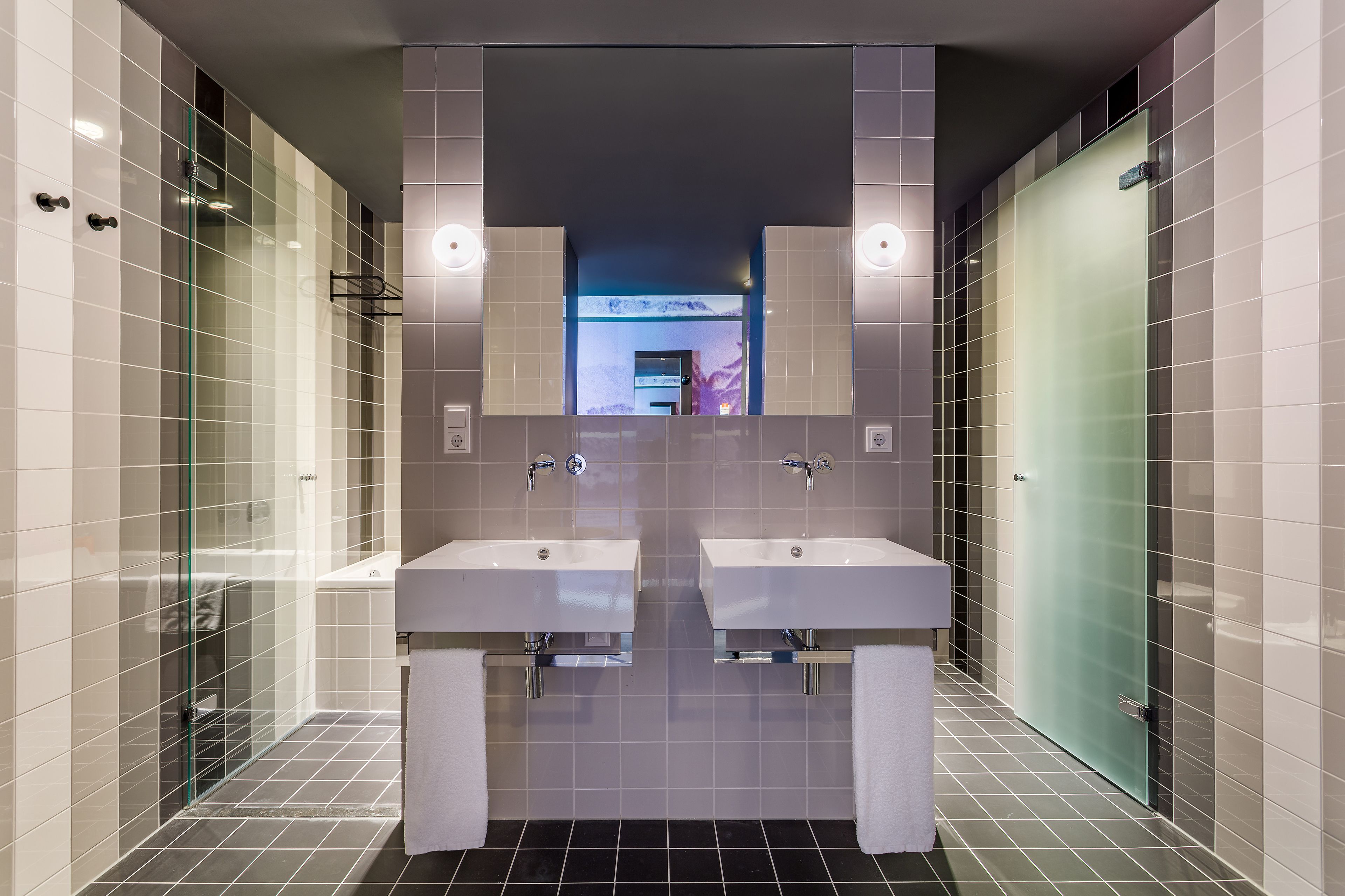 Un bagno moderno con due lavabi, cabina doccia in vetro e uno specchio sopra i lavabi.