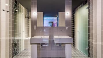 A modern bathroom with two sinks, a glass shower enclosure, and a mirror above the sinks.