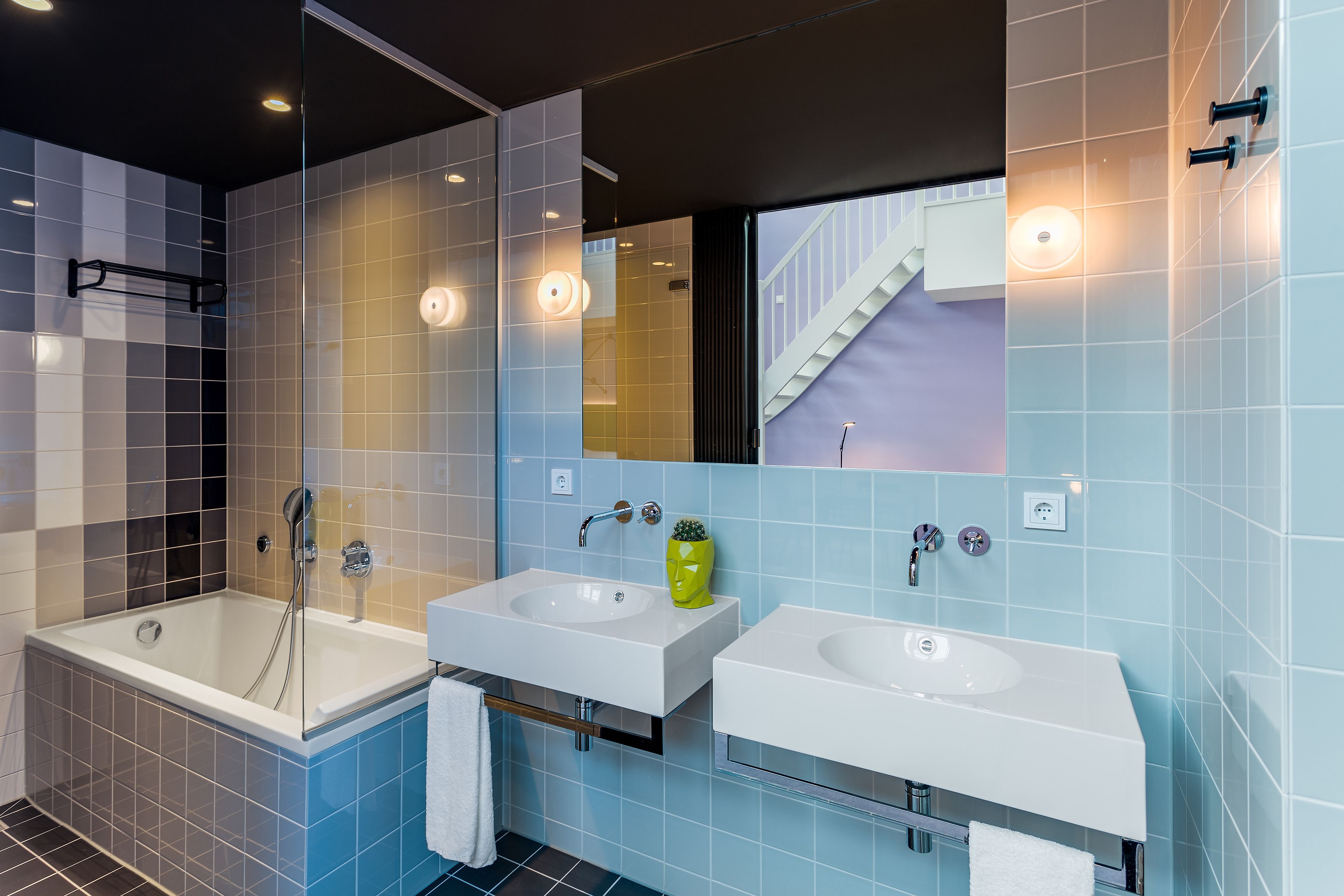A modern bathroom with two sinks, a bathtub, and a large mirror.