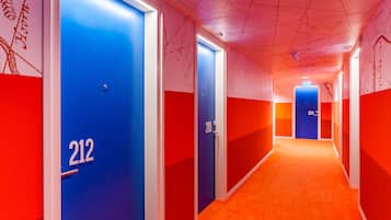 Ein Hotelkorridor mit den Fenstertüren 212 und 210, gestaltet in Rot und Blau, mit Teppichboden.